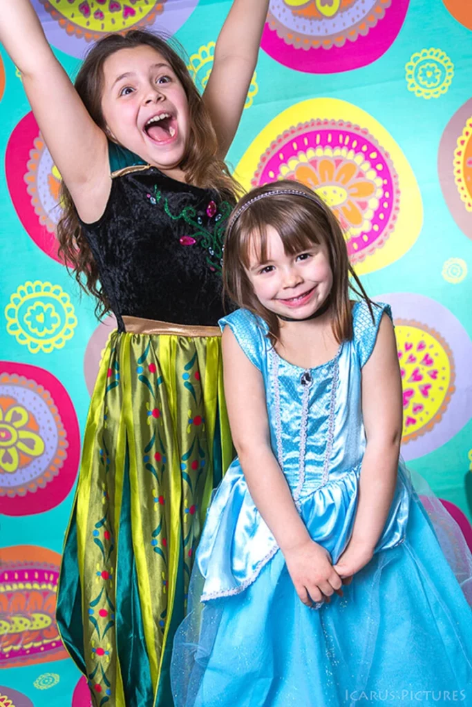 Deux enfants en costumes de princesses devant un fond coloré au studio.